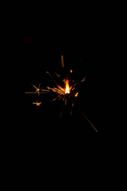 Sparkler candle used in celebrations, black background, selective focus.