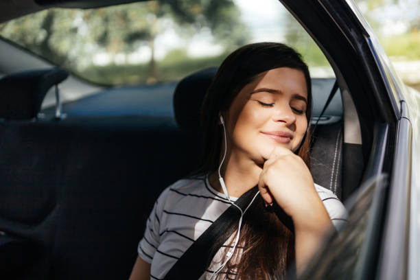 młoda kobieta relaksująca się na tylnym siedzeniu samochodu w słoneczny dzień - road trip audio zdjęcia i obrazy z banku zdjęć