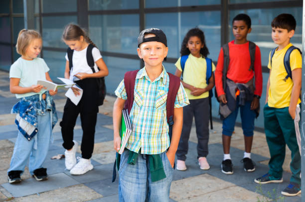 istock Cheerful tween boy standing in school campus with notebooks 1413899088