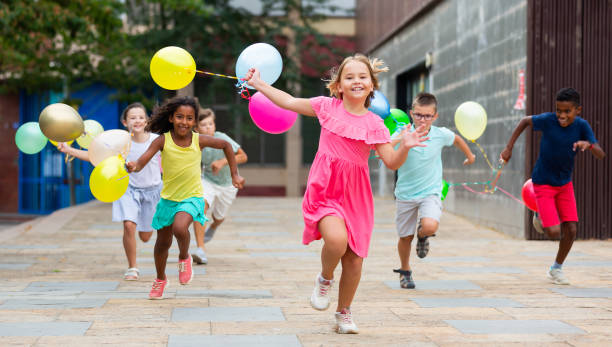 istock Kids with balloons running through streets 1413899125