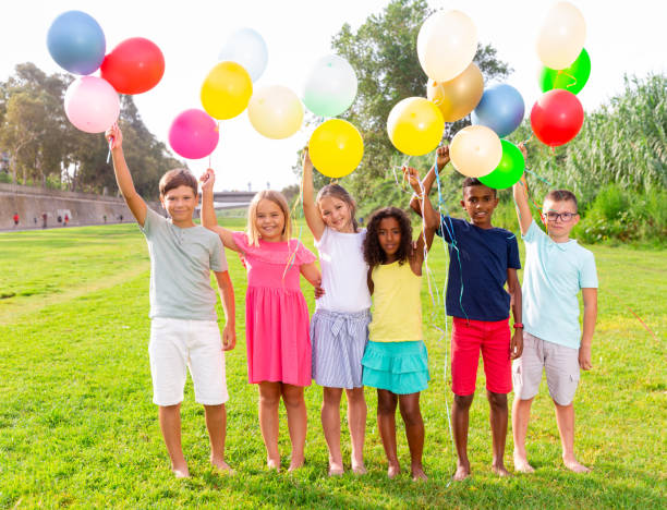 istock Cheerful tweenagers with colored balloons posing together in summer park 1413899134