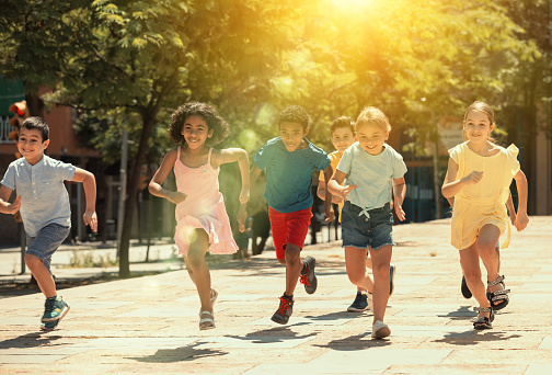 Grupo de niños alegres corriendo por la calle de verano photo