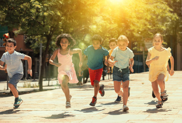 Group of joyful children running down the summer street stock photo