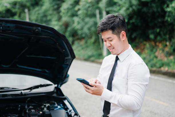 istock Asian businessman broken car engine breakdown his use mobile calling insurance smartphone problem, Accident emergency on the road concept. 1413902591