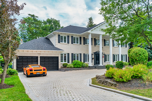 A Lamborghini luxury sports car is parked on the driveway of a large house in the affluent Mississauga Road district of Mississauga, Ontario, Canada on a cloudy day.