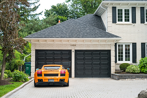 A Lamborghini luxury sports car is parked on the driveway of a house in the affluent Mississauga Road district of Mississauga, Ontario, Canada on a cloudy day.