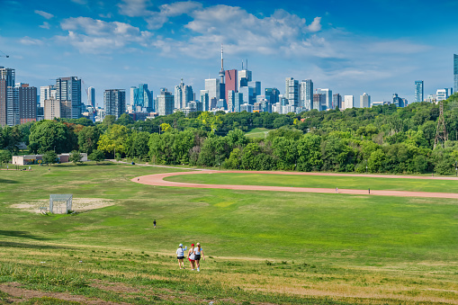 Three women walk in Riverdale Park in Toronto, Ontario, Canada on a sunny day.