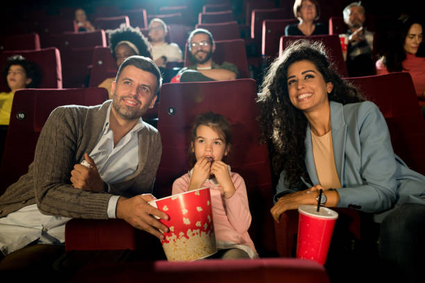 Girl and her mom and dad enjoying at the cinema stock photo