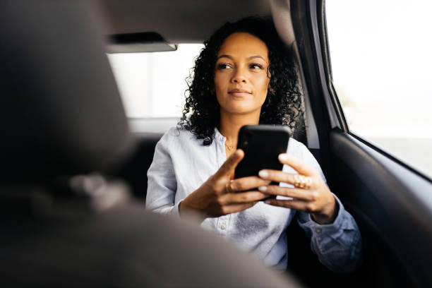 istock Businesswoman using smartphone in the car 1413907496