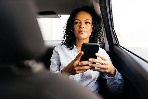 Businesswoman using smartphone in the car
