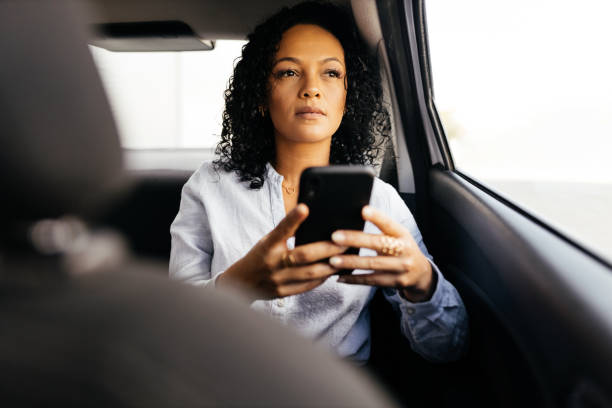 istock Businesswoman using smartphone in the car 1413907497
