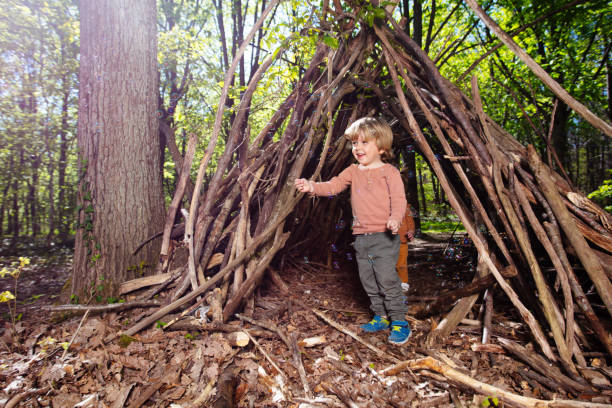 istock Blond boy play with soap bubbles in forest hut of branches 1413908175
