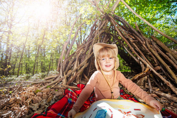 istock Child in hat with treasury hunt map over hut of branches 1413908186