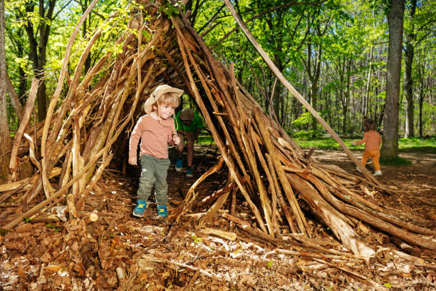 istock Boy with boy-scout hat plain in the forest hut of branches 1413908210
