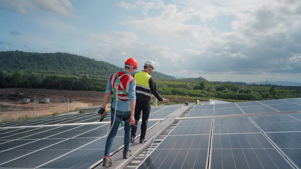 istock Team engineer or technicians or contractor wearing safety equipment to prevent falls from heights, installing, check the working system and maintenance solar panel of solar power plant to produce electricity on the roof of factory building. 1413910048