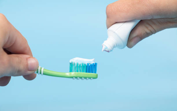 toothpaste is applied to the toothbrush,tooth brushing in hand on blue background stock photo