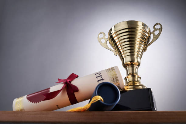 golden trophy and scroll of certificate against gray background