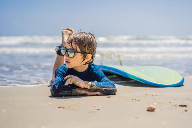 Young surfer, happy young boy at the beach with surfboard.