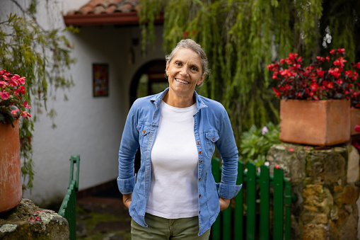 Happy Latin American senior woman smiling outdoors outside her house  and looking at the camera