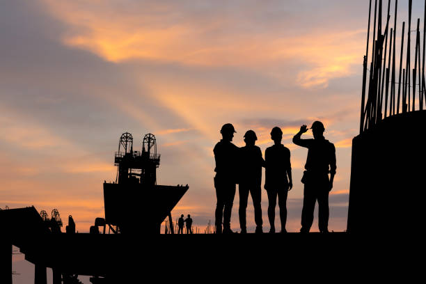 istock Silhouette of Engineer and worker team checking project at building site background, Infrastructure construction site at sunset in evening time 1413928286
