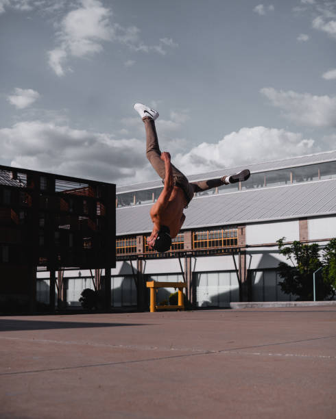 istock Dark-haired Latin man doing a backflip on an open site. Man performing a stunt in the park. Hispanic boy practicing parkour in the park. 1413932819