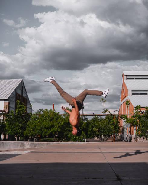 istock Latino man doing a somersault in mid-air. Hispanic boy doing an extreme flip. Man performing a stunt in the park. 1413932820