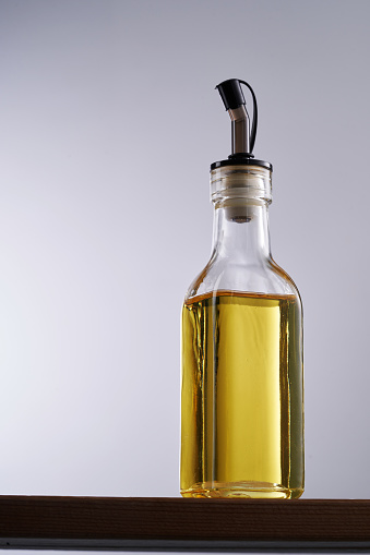 Closeup of an oil and vinegar dispenser with olive oil on a white background