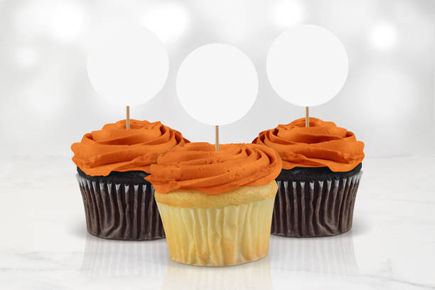 Halloween Orange Cupcake Topper Mockup Three orange frosted cupcakes in a minimalistic kitchen scene. Will they be a treat or a trick this Halloween? halloween cupcake stock pictures, royalty-free photos & images