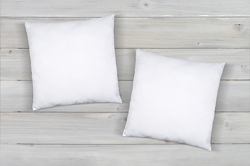 Two white throw pillows taking a nap on a modern gray wood background