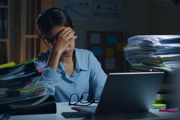 istock Young Asian office employee feeling tired, fatigue, exhausted while working overtime at night in office 1413937575