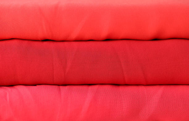 Close-up of red rolls of knitted fabric texture background. Cloth with different color shades of red backdrop