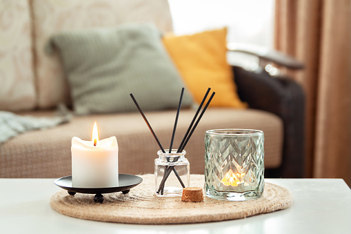 Scented candles and aroma incense sticks on table in living room. Aromatherapy, home fragrance. Concept of home relaxation and anti stress