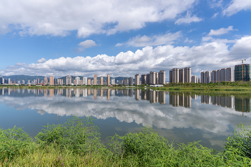 The grassland and lake of the ecological park reflect the image of the city in Putian,Fujian Province, China