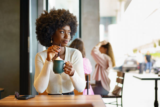 istock Young afro woman taking break and drinking coffee in cafe 1413947674