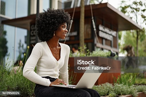 istock Young african american businesswoman working using laptop sitting on the bench in the city 1413950024