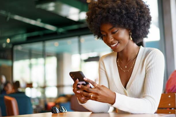 istock Young afro woman using mobile phone at coffee shop 1413950709