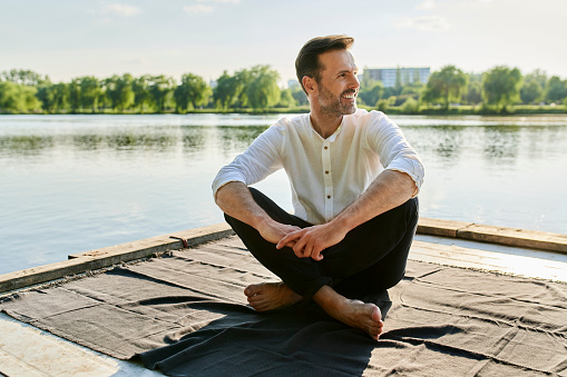 Portrait of a handsome man sitting on a deck by a lake on a summer afternoon