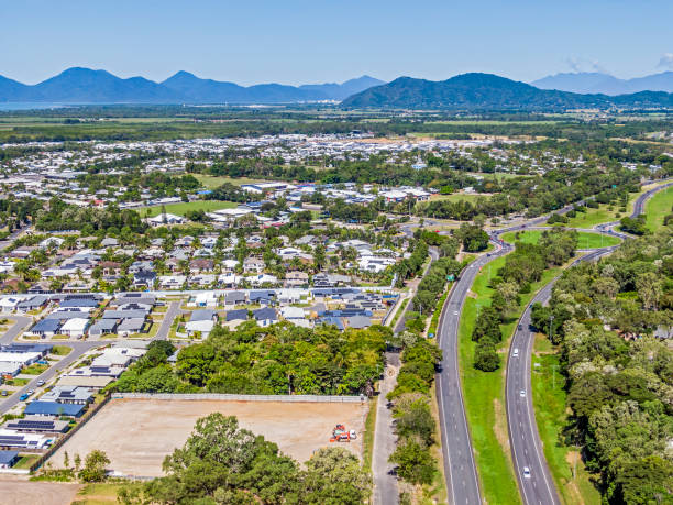 vista aérea del suburbio establecido de cairns con nuevo desarrollo de viviendas, autopista principal y rotonda, espacio verde de reserva y rangos en la distancia - cairns fotografías e imágenes de stock