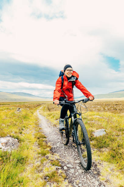 Woman cycling from Dalwhinnie, along Loch Ericht to Culra Bothy in the Highlands of Scotland.