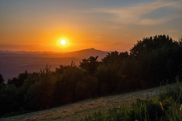 Sunset over mountains, forest and meadow, hill Jested on horizon, Czechia. stock photo
