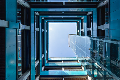 Color image depicting an abstract high angle view of a concrete spiral staircase. We can see the blurred motion of a group of people walking up and down the staircase, giving the impression that they are moving fast.  Room for copy space. ***image taken in City Hall, London, UK, a publicly owned building freely accessible to the public without entry fees or photographic restrictions***