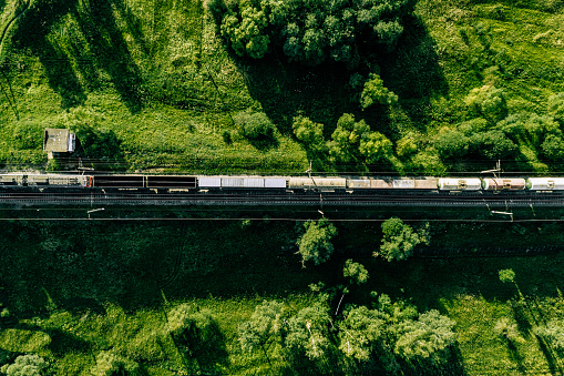 Aerial view of Railway railroad tracks and cargo train through countryside in summer