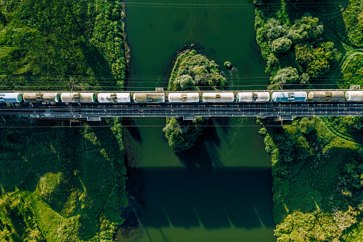 Aerial view of Railway railroad tracks and cargo train over the river in summer