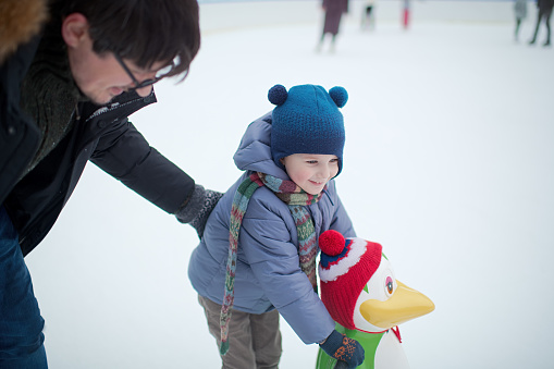 Child learns ice-skating using a helper penguin