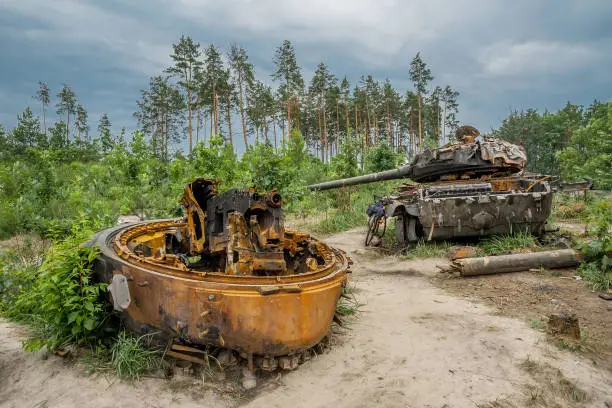 The rusty hull of a broken tank is overgrown with grass