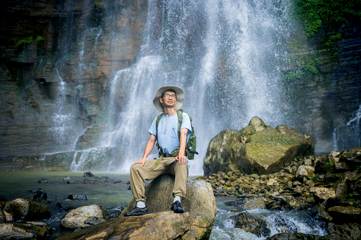 A man sitting on rock resting by waterfall