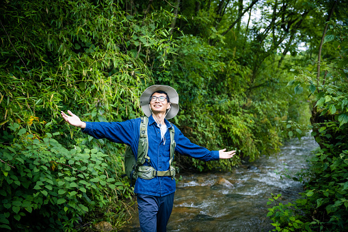 Male hiker crossing the stream in forest