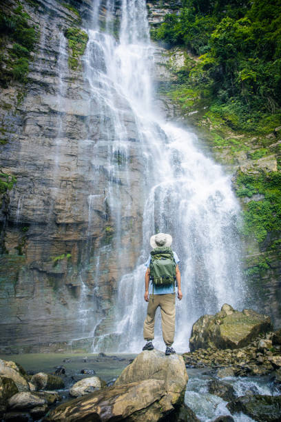 Tourist standing in front of a mountain waterfall