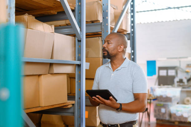 Warehouse manager, worker and logistics boss taking inventory with tablet. Online apps simplify tasks for fast, efficient courier and delivery service. Using modern technology to get quicker results stock photo