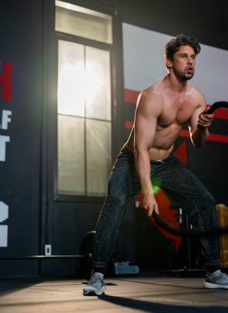istock Handsome and muscular white male doing battle rope training exercise in a gym 1413976988